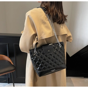 Close-up of quilted black PU leather bag with silver chain strap and metal snap closure