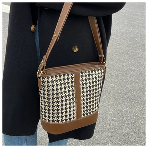 Détails du tissu pied-de-poule et finitions en cuir marron sur le sac seau