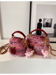 Pink tweed crossbody bags with red handles and cute plush charms on a white pedestal