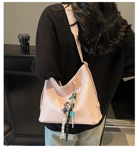 Detail of pink shoulder bag featuring embossed texture and a cute character pendant