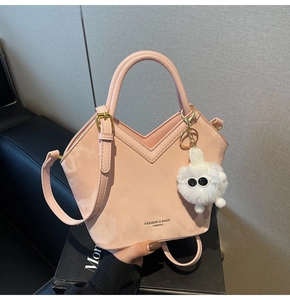 Détail du sac à main en cuir rose clair avec pendentif monstre et finition brillante