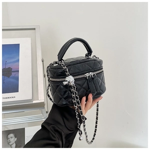 Détail du mini sac vanité noir matelassé avec chaîne argentée et poignée élégante