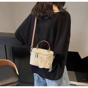 Détail du sac boîte vintage crème avec poignées marron et nœud décoratif rayé