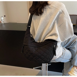 Close-up of black quilted hobo bag featuring diamond stitching and wide woven shoulder strap