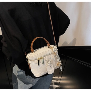 Détail du sac boîte en cuir blanc cassé avec poignées brunes et foulard en soie élégant