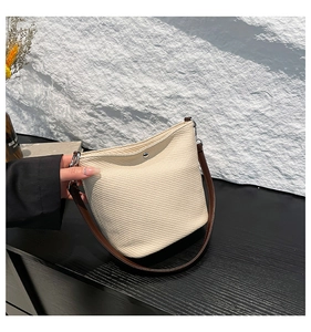 Détail du sac seau tissé crème avec bouton pression argenté et bandoulière en cuir