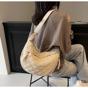 Close-up of beige quilted crescent bag with diamond stitching and woven rope zipper pull