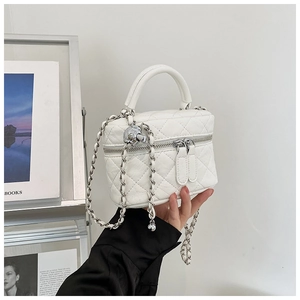 Gros plan du mini sac matelassé blanc avec breloque crâne et bandoulière chaîne