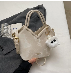 Gros plan du sac à main crème à motif marbre avec coupe en V et breloque en peluche douce