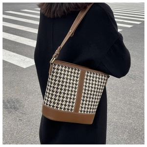 Détail du sac seau rétro à motif pied-de-poule avec bordures en cuir marron en extérieur