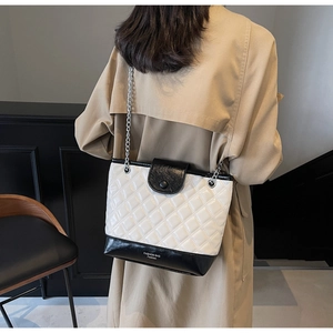 Detail of quilted bucket bag with silver chain strap and black and white contrast leather