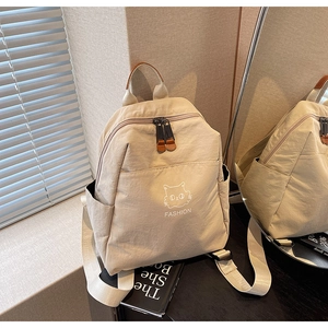 Close-up of minimalist beige nylon backpack featuring cute cat print and leather details