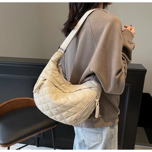 Close-up of quilted beige half-moon hobo bag showing woven cord zipper pull and wide strap