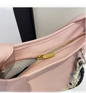 Detail view of pink leather underarm bag with smooth metal zipper and woven cord accent