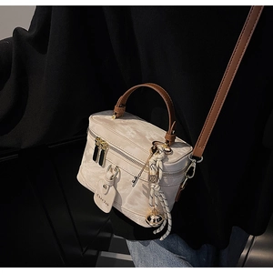 Détail d'un sac boîte rétro à motif marbré avec ferrures dorées et breloque en cuir
