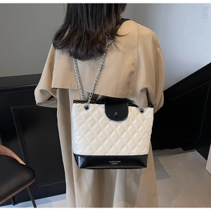 Detail showing contrast quilted chain bucket bag on a model with neutral background