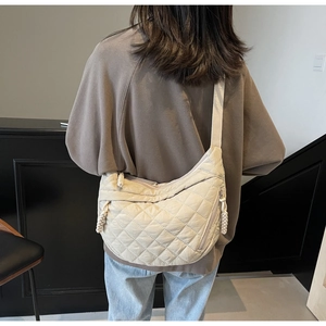 Detail of beige quilted crossbody bag showing diamond stitching and chunky rope zipper knot