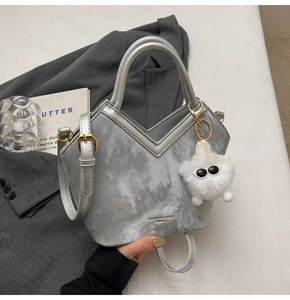 Vue détaillée du sac bandoulière gris argenté texture marbre avec breloque monstre en peluche