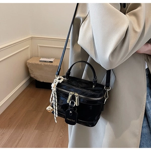 Détail d'un sac boîte noir brillant avec foulard en soie et bandoulière ajustable