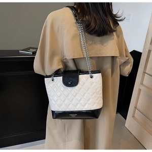 Detail of black and white quilted bucket bag with silver chain strap and fashion text