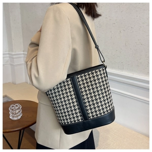 Detail of houndstooth bucket bag with black leather trim and contrast white stitching