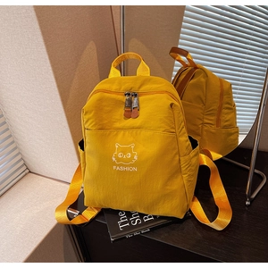 Detail of a bright yellow waterproof nylon backpack with cat print and dual zippers