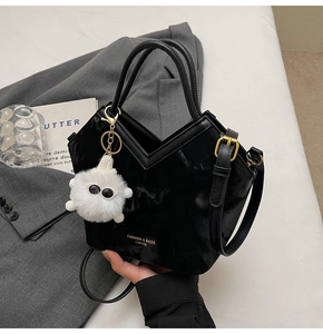 Détail du sac à main noir en V avec pendentif en peluche et texte doré chic