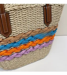 Detail of woven straw tote bag with multi-colored stripes and stitched leather handles