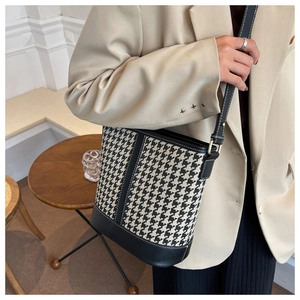 Détail du sac seau à motif pied-de-poule avec bordure noire et coutures contrastées
