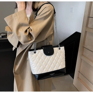 Close-up of the black and white quilted tote bag with silver chain and fashion text detail