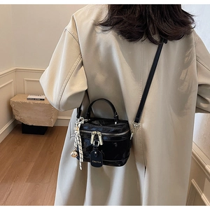 Détail d'un sac boîte en cuir verni noir avec foulard en soie et zips dorés doubles