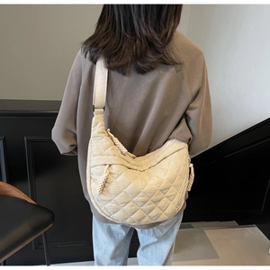 Detailed view of beige quilted dumpling bag with adjustable wide strap and woven zip puller