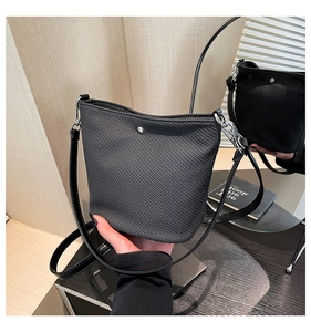 Détail du sac seau noir texturé montrant le bouton pression argenté et la bandoulière