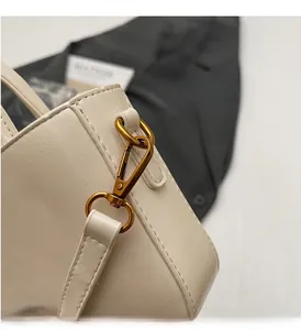 Close-up of vintage gold hardware and stitching details on a cream faux leather handbag