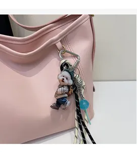 Detail of a dog charm in stripes and denim hanging on a pink leather shoulder bag