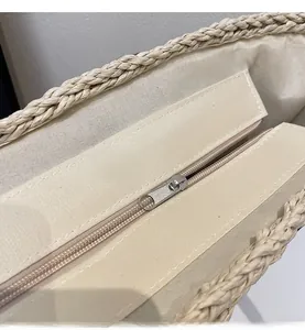 Detail of the smooth silver zipper and canvas lining on the woven straw shoulder bag