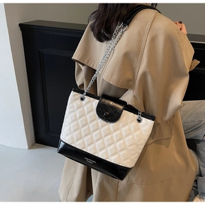 Detail of quilted bucket bag with chain strap and contrast bottom on model