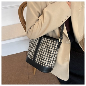 Détail du tissu à motif pied-de-poule et garniture en cuir noir sur un sac seau vintage