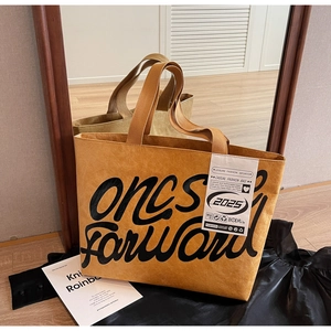 Détail d'un grand sac fourre-tout marron avec texture plissée et étiquettes mode