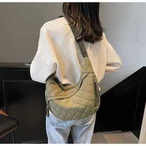 Quilted green crescent bag showing large capacity and adjustable strap on a model