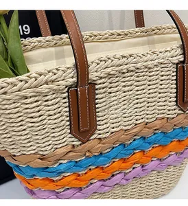 Detail of straw tote bag showing reinforced leather handles and vibrant woven stripes
