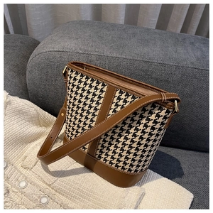 Détail du tissu pied-de-poule et finitions en cuir marron d'un sac seau à la mode