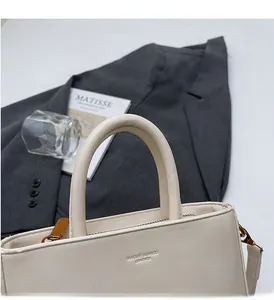 Detail of ivory leather handbag with golden metal hardware and embossed logo