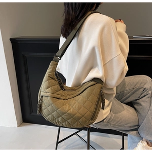 Detail of olive green quilted crescent bag showing stitching and woven zipper puller