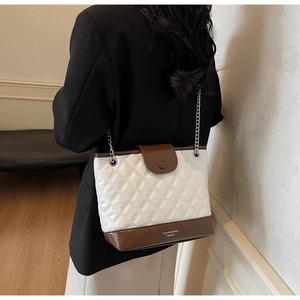 Detail of quilted white and brown bucket bag featuring silver chain strap and metal finish