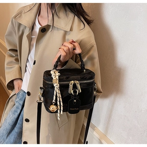 Détail du sac boîte vintage noir avec fermetures dorées et breloques tissées