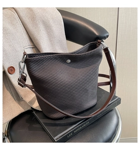 Détail du sac seau tissé foncé avec bandoulière en cuir marron et crochet argenté