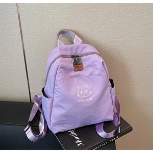 Detail view of light purple nylon backpack featuring cat print and front zipper pocket