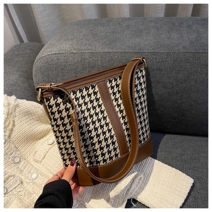 Détails du motif pied-de-poule et du cuir marron sur un sac seau élégant
