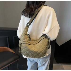 Quilted olive green crescent bag with wide shoulder strap shown on a model